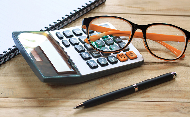 A picture of a pen, calculator and a orange reading glasses