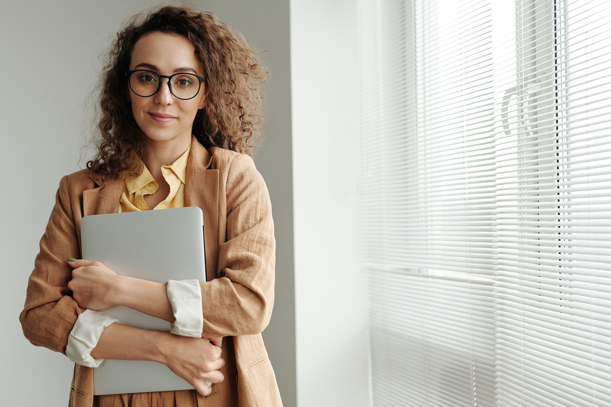 A picture of a woman with eyeglasses holding a laptop