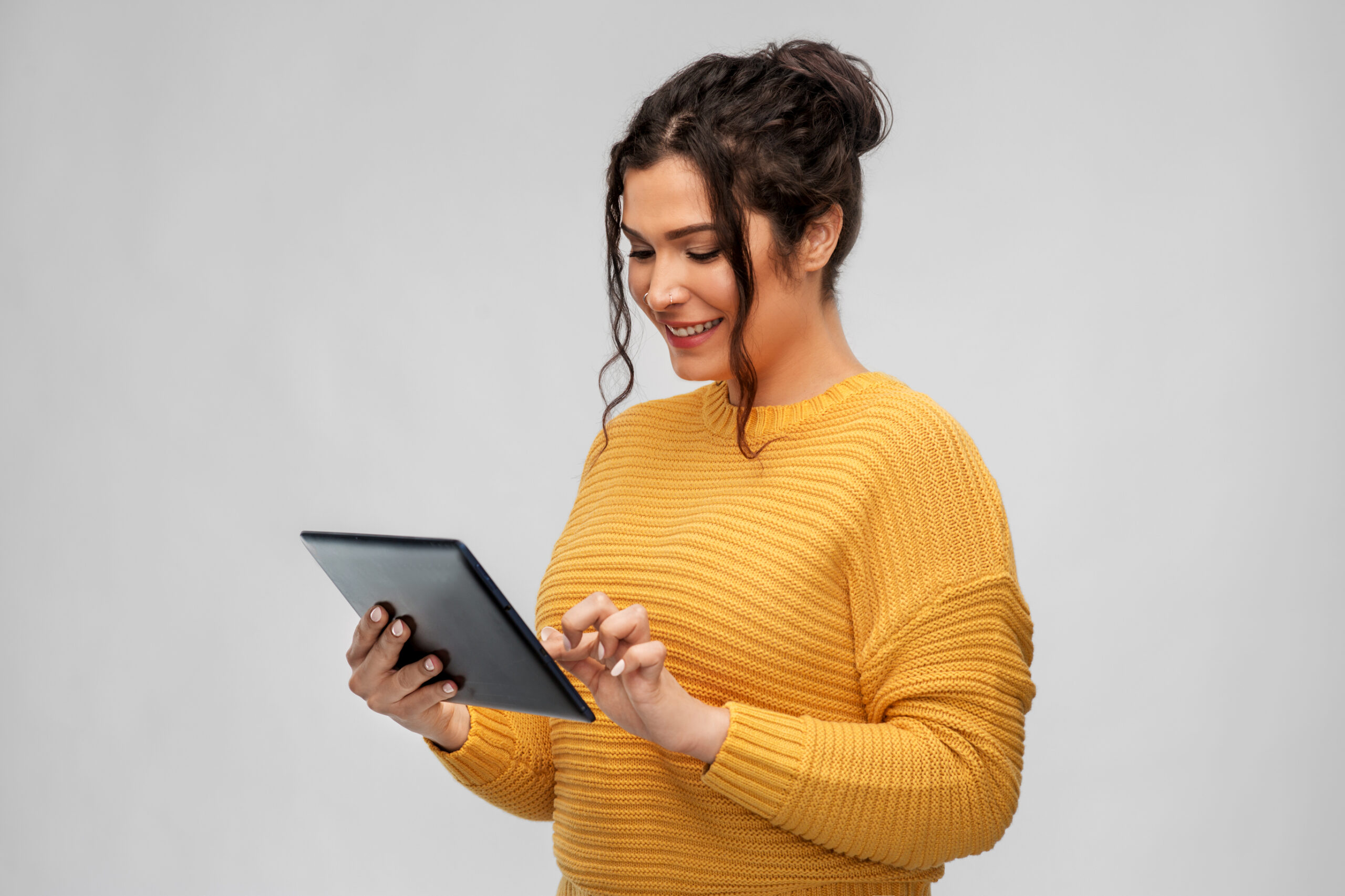 woman in a yellow sweater looking at a tablet