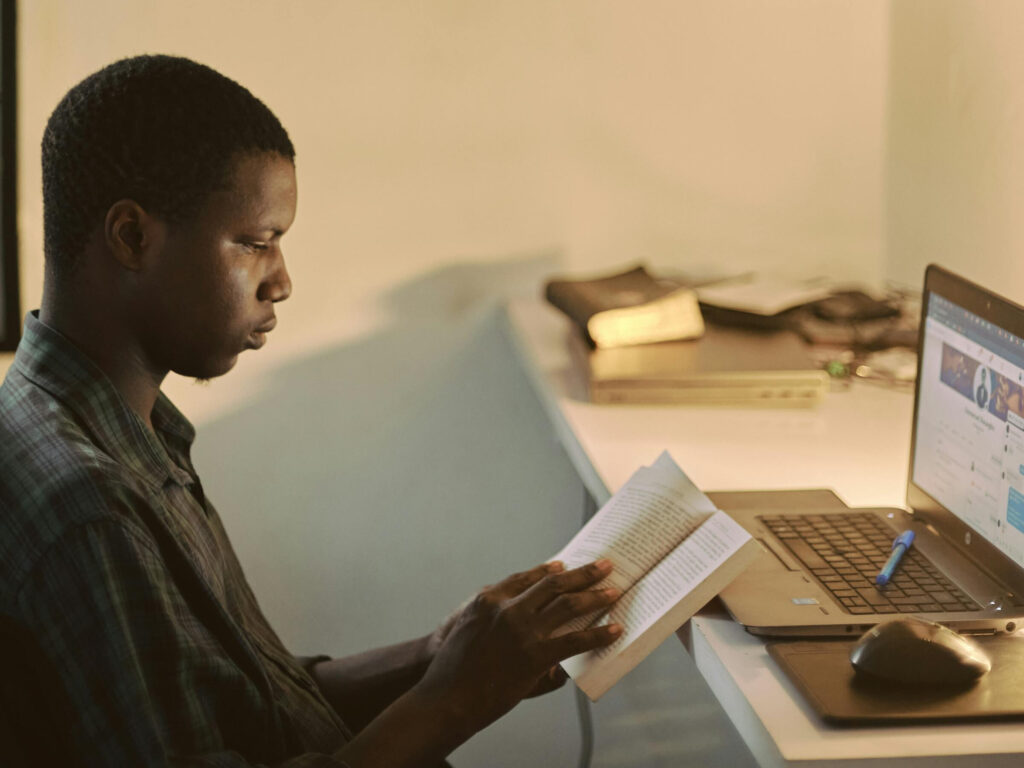 an african american male sitting at his desk reading a bible aligning his career with his faith
