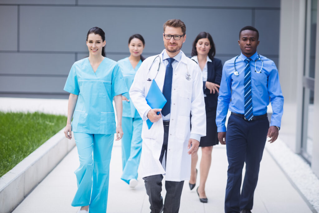 Group of healthcare professionals and administrators walking together outside a medical facility, representing careers in healthcare administration