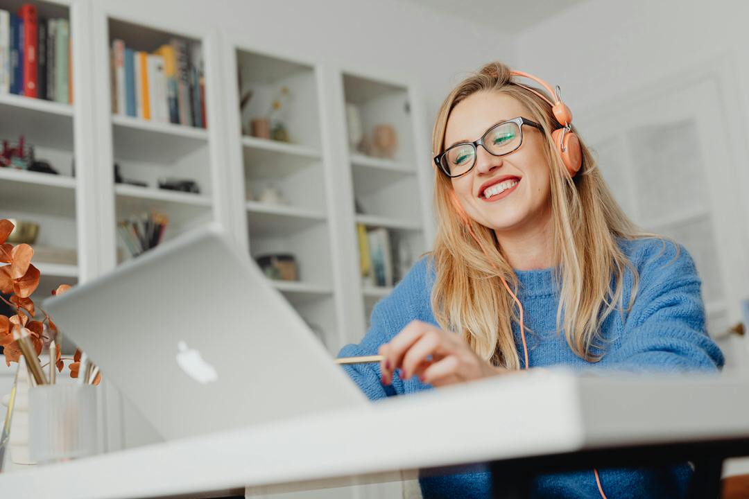 A working adult student smiling while studying on a laptop at home